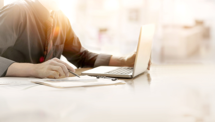 Close up of hand of business man working document and laptop in office morning light.